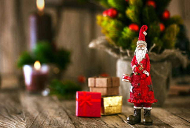 Puppe Weihnachtsmann vor kleinen Geschenkpäckchen und Tannenbaum