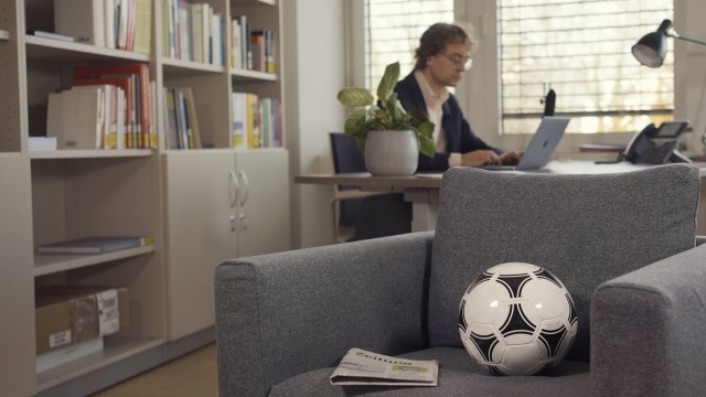 Simon Meier-Vieracker am Schreibtisch, im Vordergrund ein Sessel mit Fußball und Tageszeitung