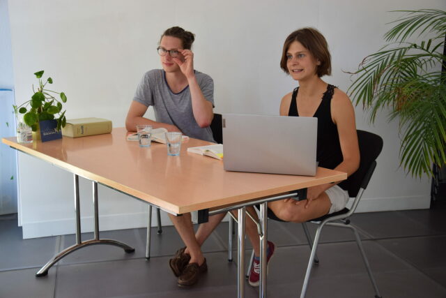 Zwei Studierende der RLC an einem Schreibtisch mit Laptop und einem Gesetzbuch.