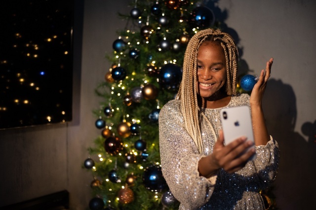 Frau mit Handy vor Weihnachtsbaum