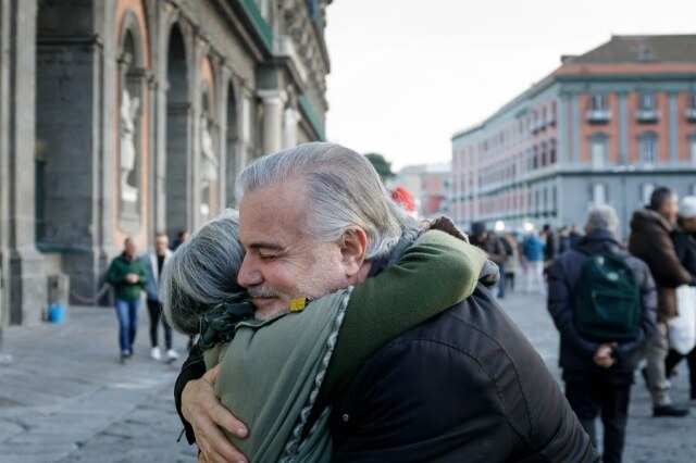 Zwei Menschen umarmen sich herzlich auf einem öffentlichen Platz.