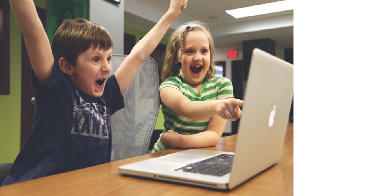 Mädchen und Junge freuen sich vor einem Laptop