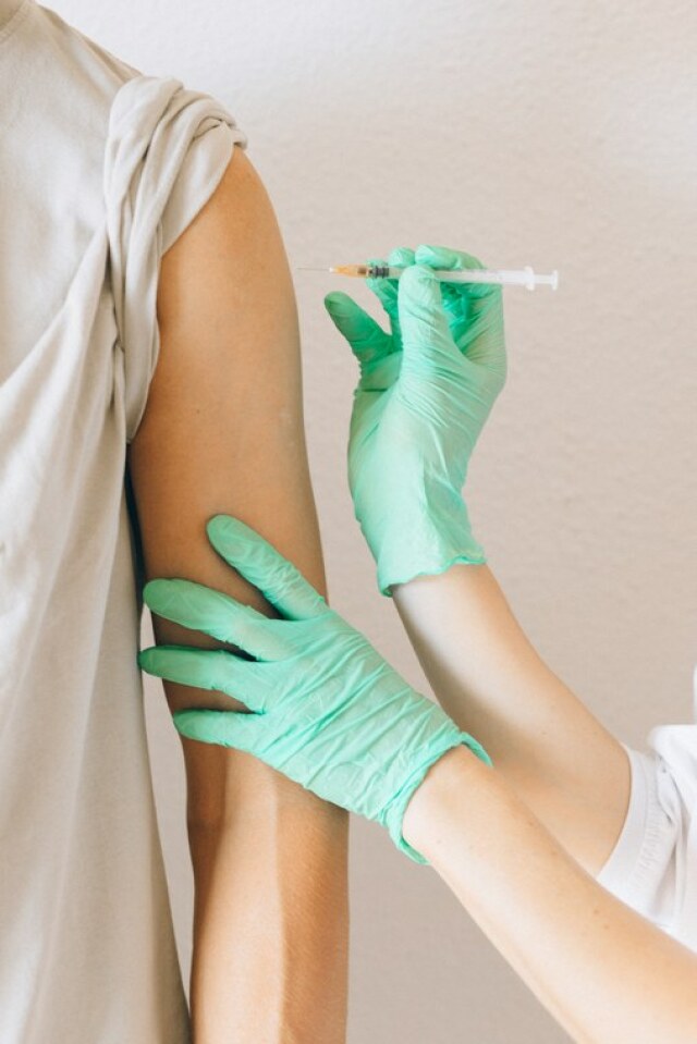 Bild einer Verabreichung der Impfung. Zu sehen sind nur die Arme des Patienten und der behandelnden Person sowie die Spritze.