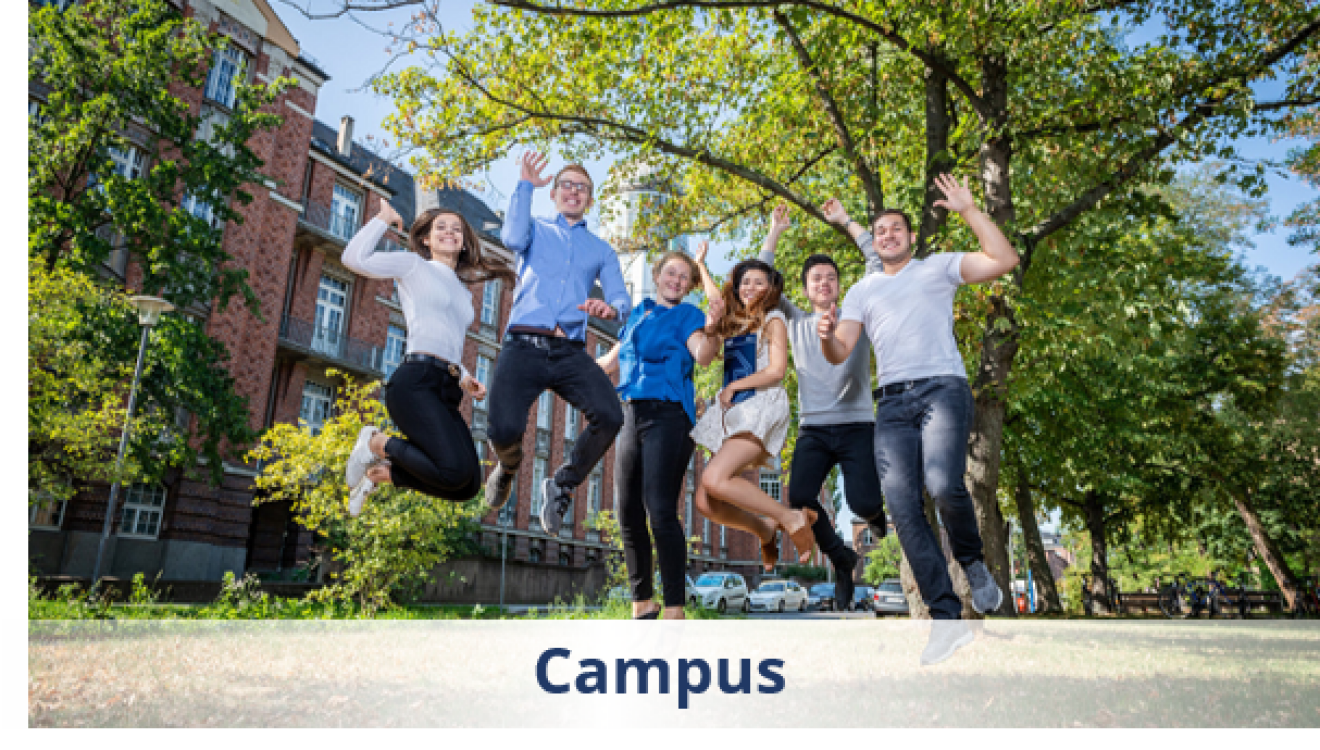 Studierende und Beschäftigte springen in die Luft vor Laubbaum und Ziegelgebäude auf dem Campus