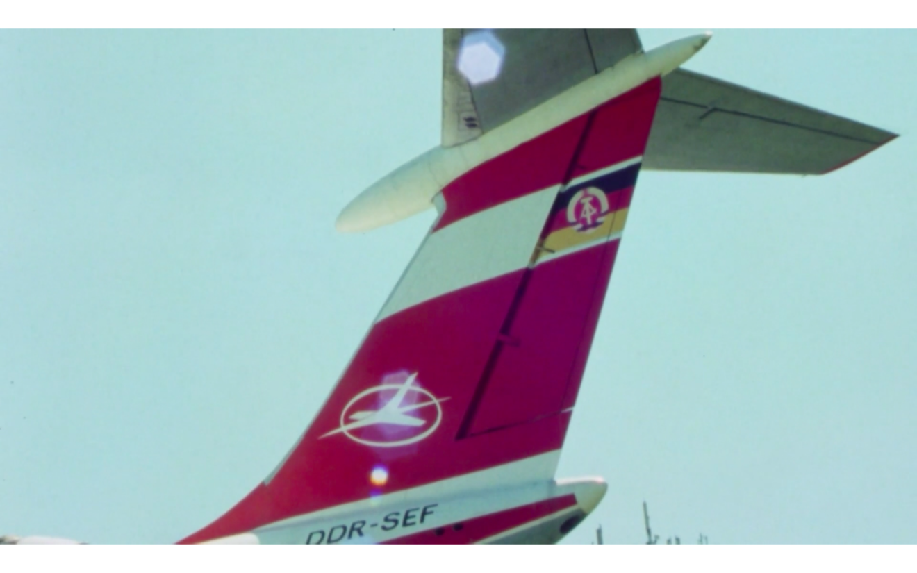 Foto eines Hecks einer Interflug-Maschine in rot-weiß mit DDR-Flagge und die Bezeichnung des Flugzeugs: DDR-SEF