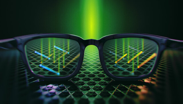 Abbildung einer '3D-Brille' mit grünen Lichtteilchen in der Mitte. Durch die Brillengläser sieht man Elektronen (blau und gelb), können sich drehen (Drehsinn von Elektronen).