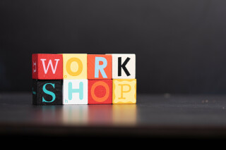 Eight colorful cubes, in two rows, against a dark background make the word 'workshop'.