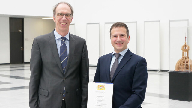 Photo: two men in a bright room. Right: Giorgio Sangiovanni; holding the certificate of appointment in his hands. On the left: Prof. Paul Pauli.