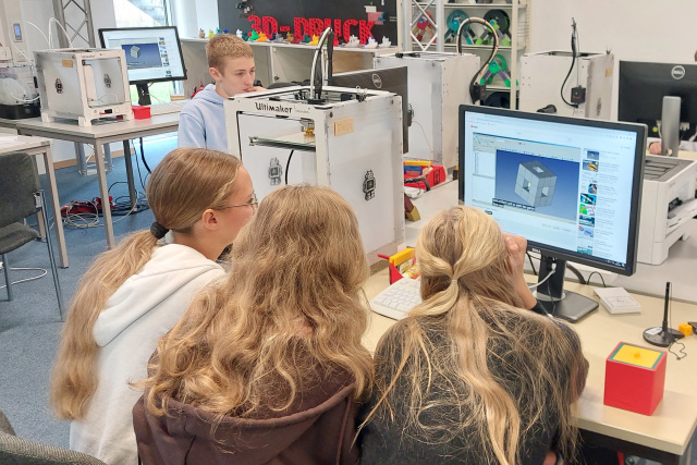 Schülerinnen und Schüler vor einem PC Bildschirm auf dem ein 3D Objekt zu sehen ist