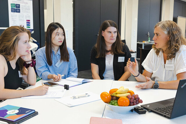 Vier Frauen sitzen um einen Tisch und diskutieren. Die beiden Personen auf der linken Seite sind Studentinnen, die beiden anderen sind die Mentorinnen.