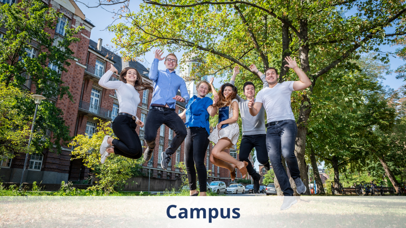 The photo shows a small group of people jumping into the air, with deciduous trees and a brick building in the background.