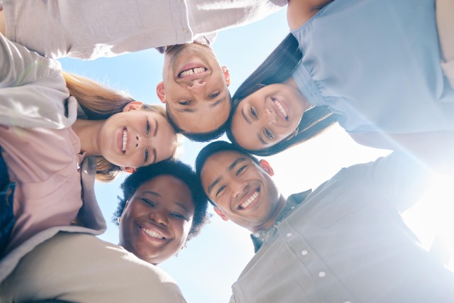 The photo shows 5 people standing together in a circle and looking into the camera from top to bottom.