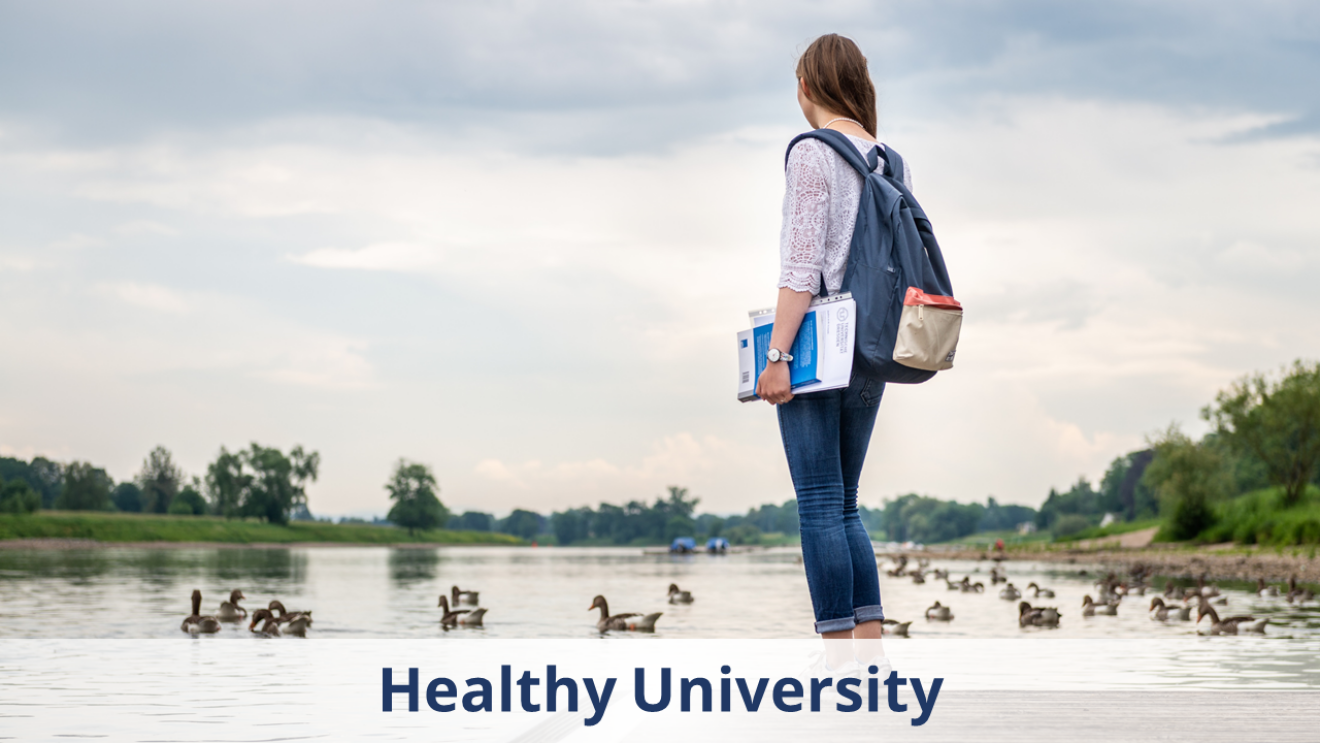 The photo shows a woman looking out over a calm body of water with lots of ducks.