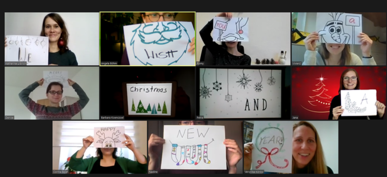 Screen shot of a Zoom meeting with people holding Christmas greetings into the camera