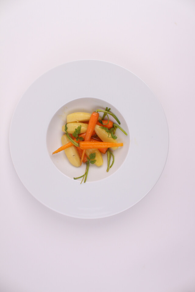 Bright yellow and organic vegetables with green accents on a white plate.