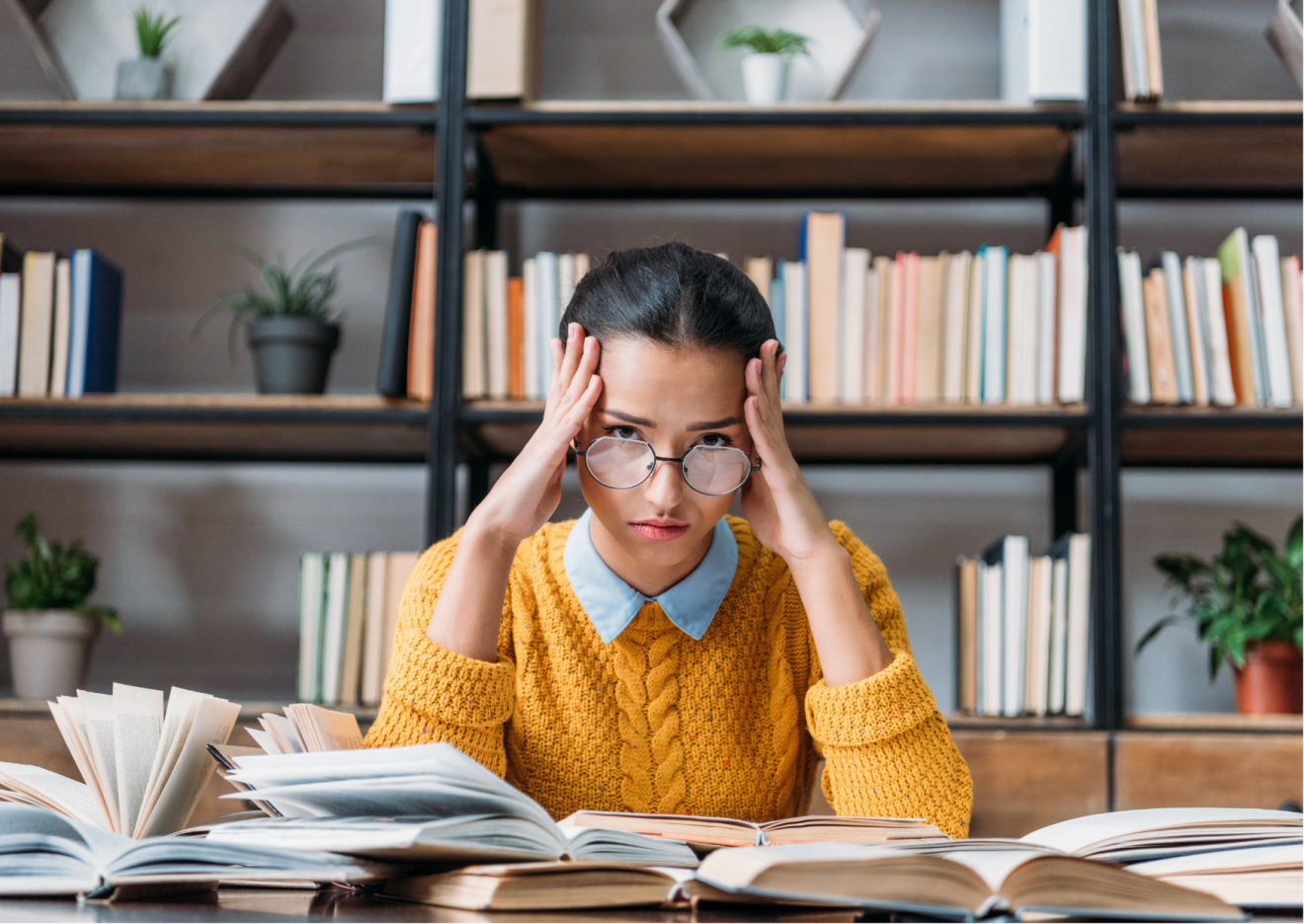 Young Woman with glasses and a yellow sweater behind a desk in distress