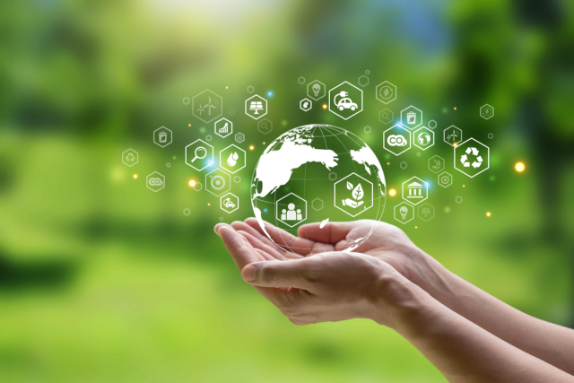 Photo of two hands holding a world before a green backdrop