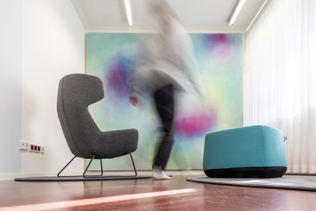 The Retreat contains an armchair and two turquoise seats, as well as a large painting. 