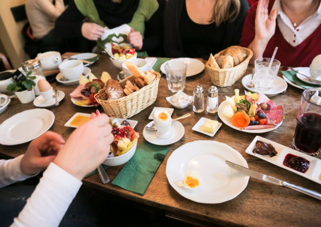 The picture shows a beautifully laid breakfast table. Several women sit at this table, eat together and share ideas.