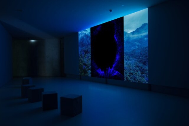 Installation view, dark blue illuminated room
