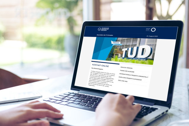 Laptop open, hands on the keyboard, the alumni magazine visible on the screen